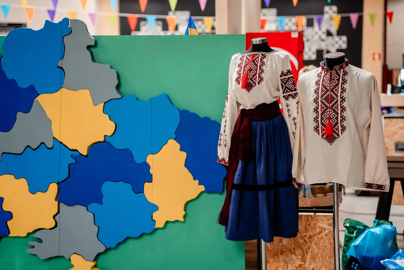 Mapa da Ucrânia feito em madeira, ao lado de camisas bordadas em exposição.