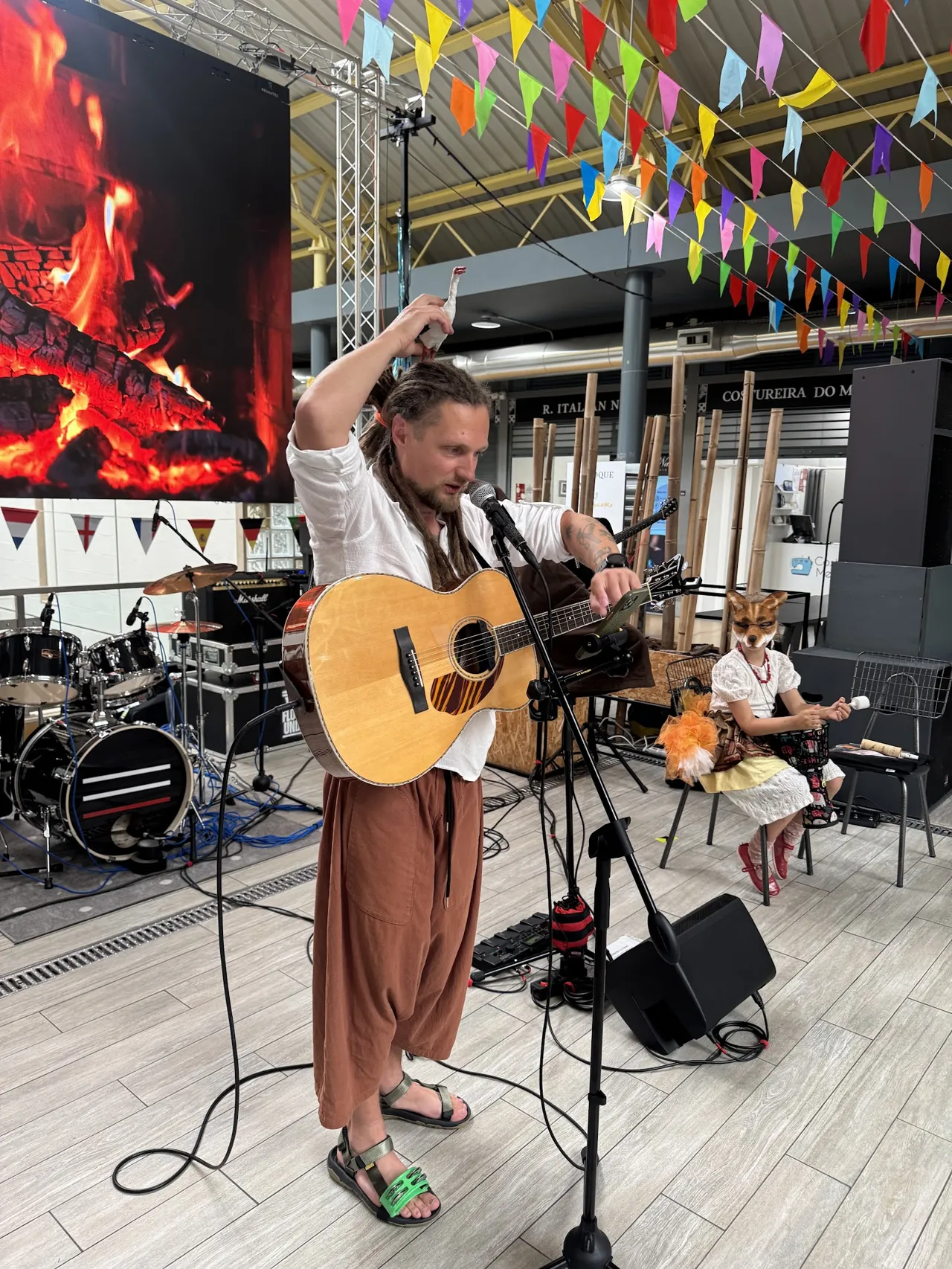 O músico do Morphom a tocar guitarra no palco, em frente a um ecrã com chamas.